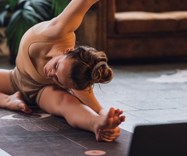 Person doing a gentle stretching yoga pose on a mat.